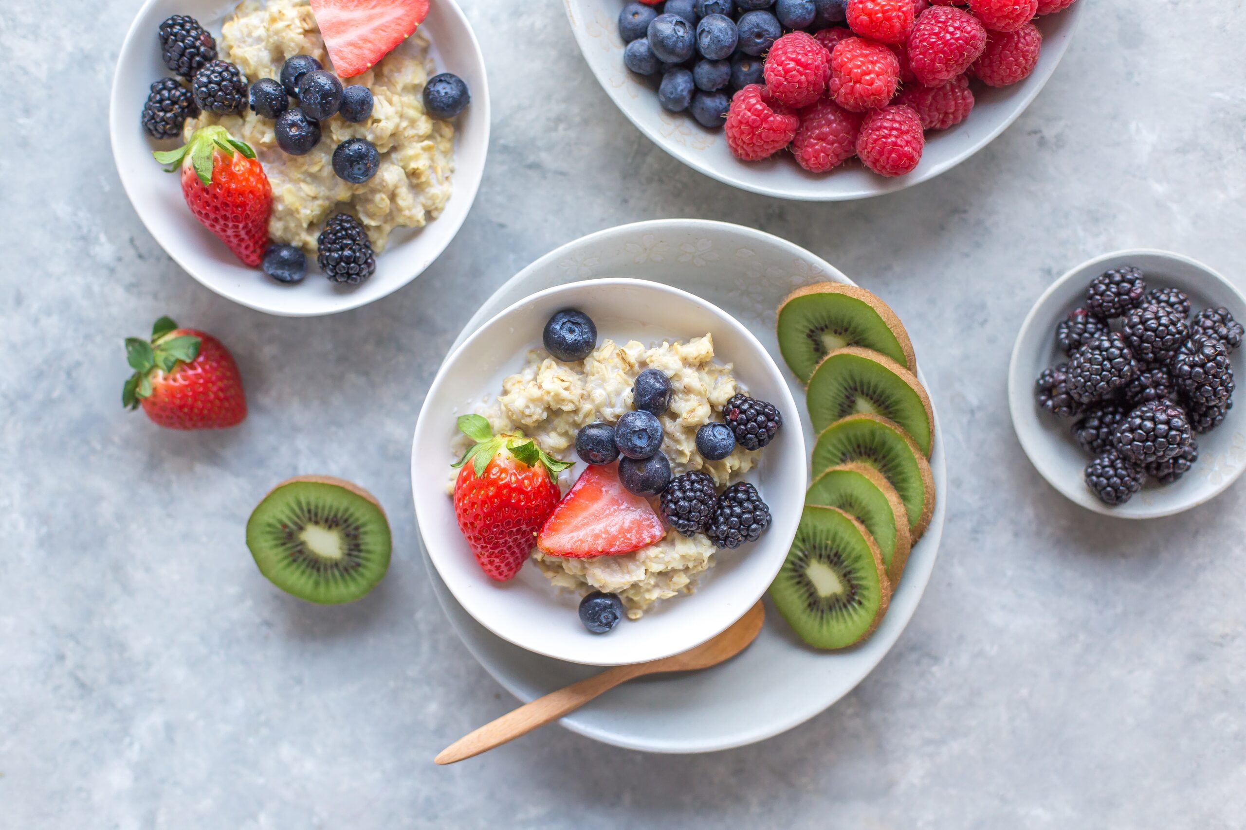 Two bowls of porridge, topped with lots of fruit like kiwis and berries