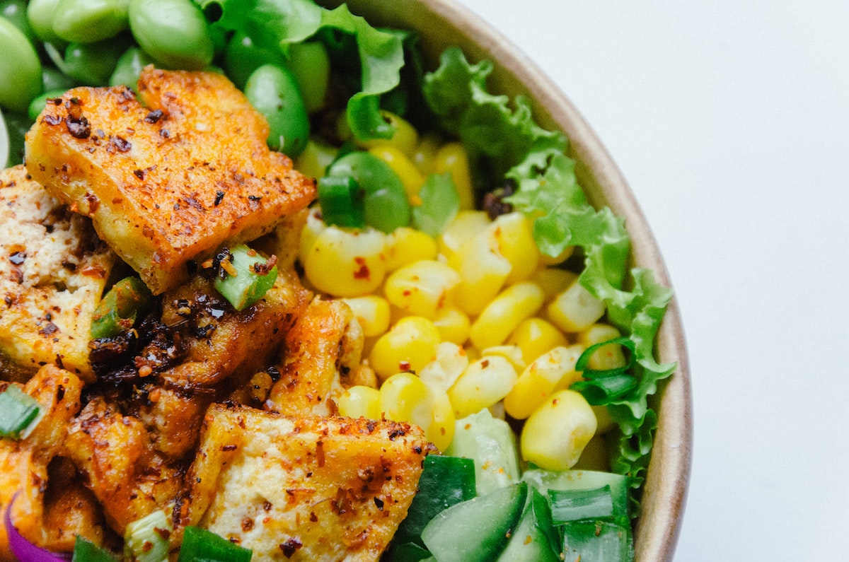 a photo of a bowl of salad made with sweetcorn, edamame beans, and fried tofu.